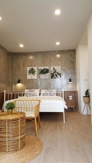 Quarto com cama, mesa de cabeceira, luminária e arte nas paredes.