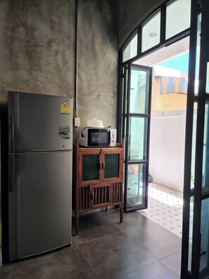 A compact kitchen with a refrigerator, microwave, and wooden cabinet. - Baankorrakang (Bangkok)