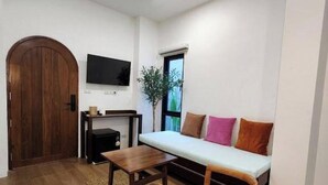 A compact living space with a sofa, a coffee table, a chair, a television, and a wooden door.