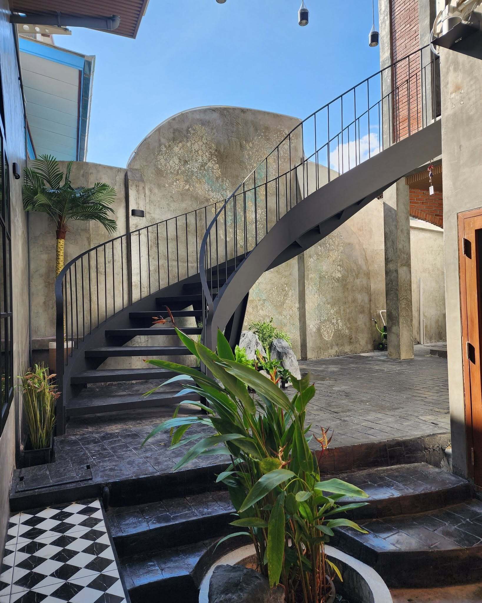 A spiral staircase with a metal railing leading to a second-floor landing.