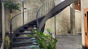 A spiral staircase with a metal railing leading to a second-floor landing.