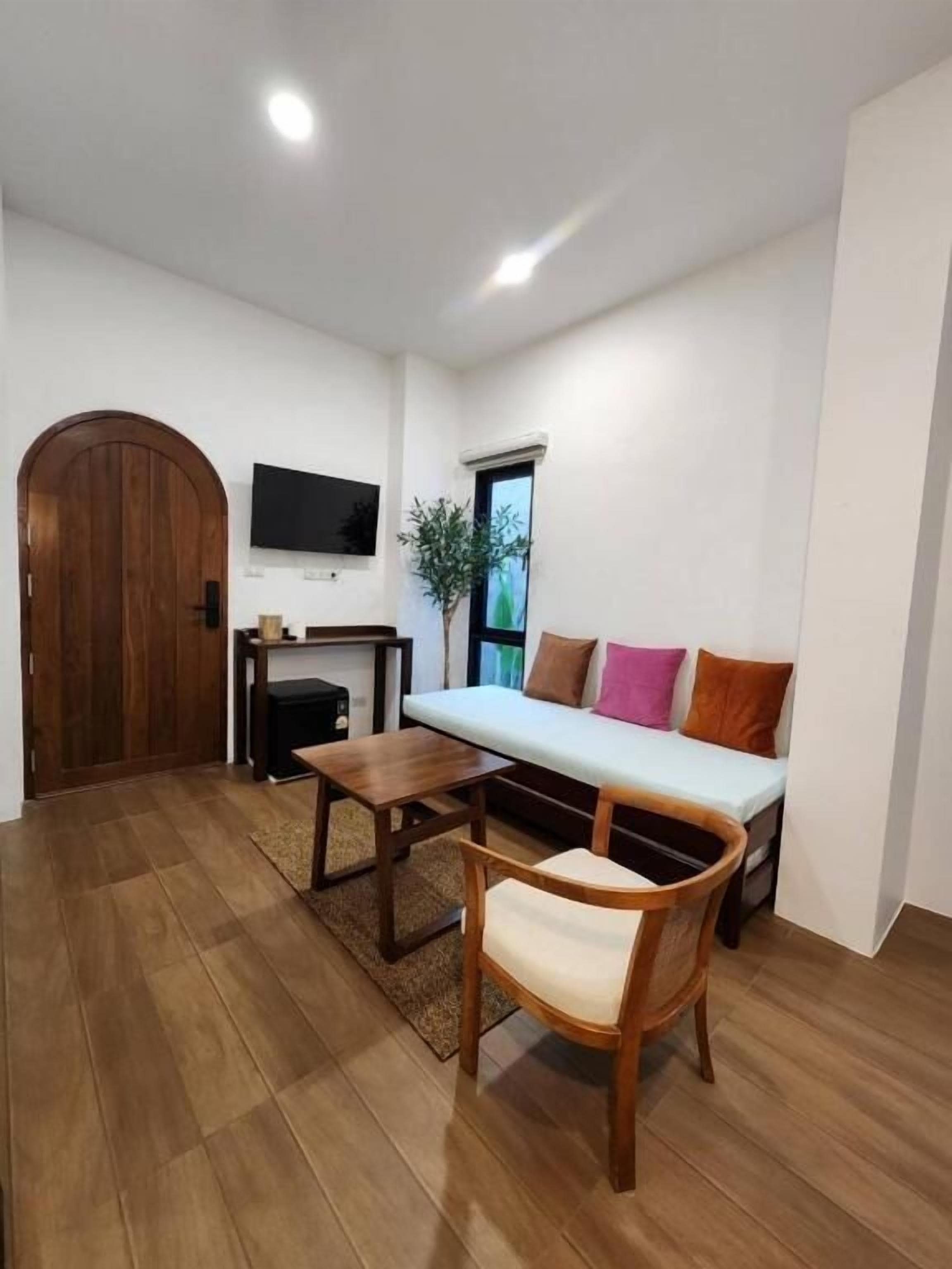 A living room with a sofa, a wooden table, a chair, a TV, and a door.