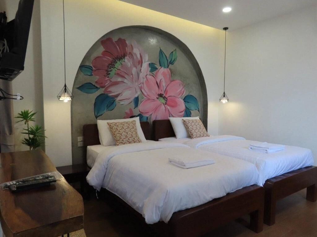 A double bed with white linens, a wooden headboard, and a large floral painting above it.