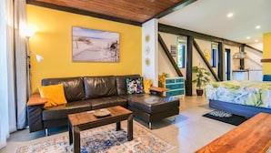 A living room with a sofa, coffee table, and a painting on the wall.