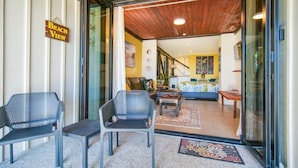 A room with a wooden ceiling, a sofa, a coffee table, and a chair.