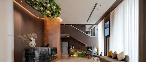 A modern lobby with a reception desk, seating area, and a staircase.