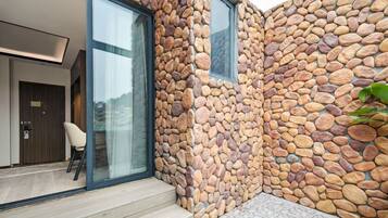 A modern building with a stone exterior, a glass door entrance, and a small outdoor seating area.