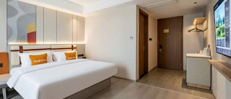 A hotel room with a large bed, a desk, and a television.
