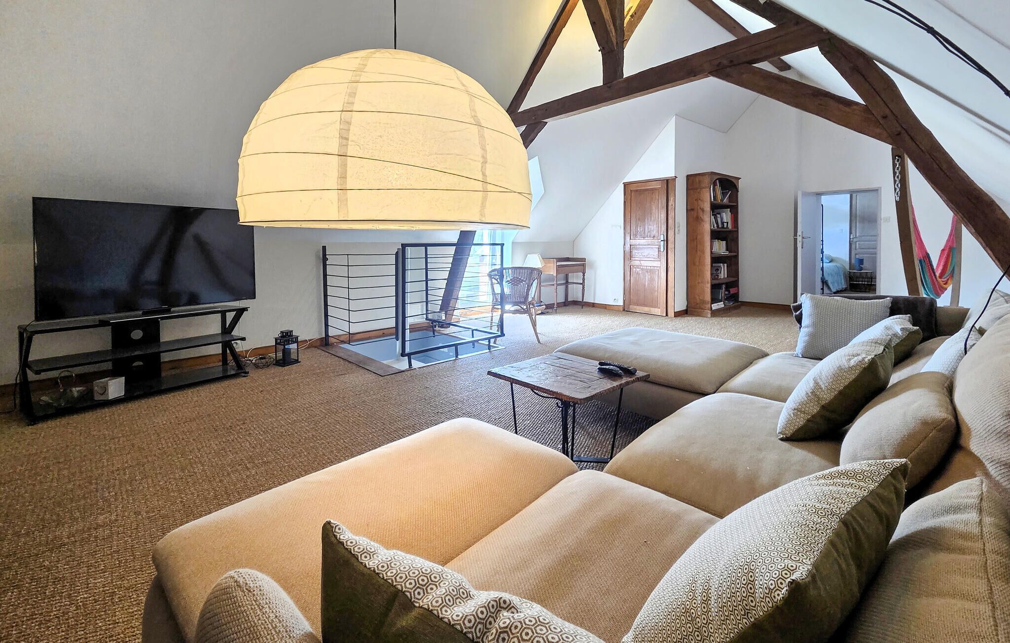 Un salón amplio con un sofá grande, un televisor y una lámpara de techo original.