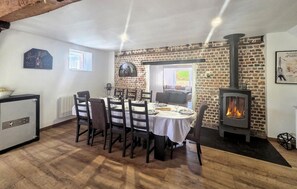 A dining area with a brick wall, a fireplace, and a view of the outdoors. - Villa avec piscine privée (CharonVille)