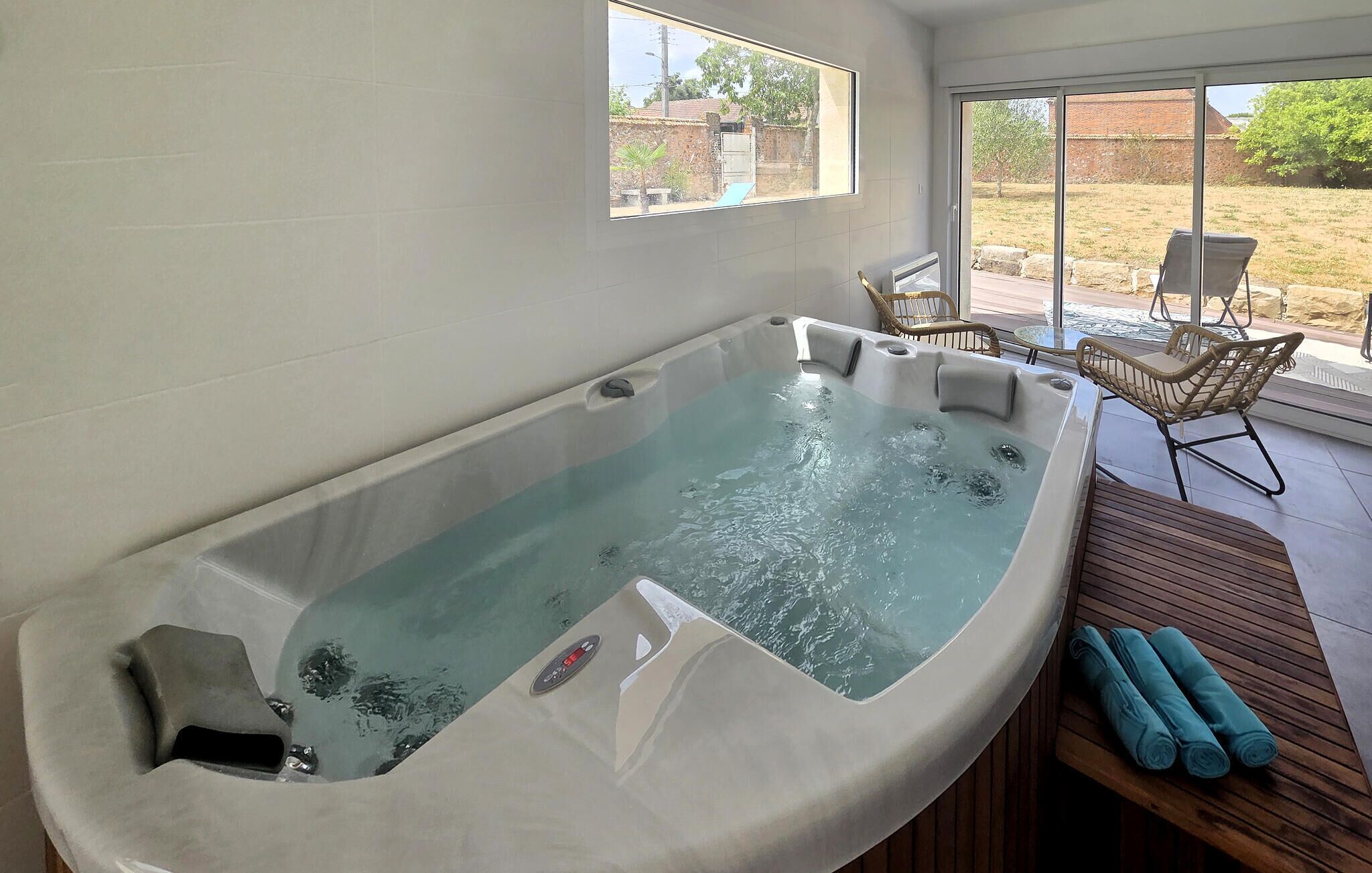 A spa area with a hot tub, wicker chairs, and a view of the outdoors.