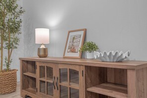 A wooden cabinet with a lamp, a framed picture, and a plant on top. - Cozy 3 bedroom Townhome In North Laredo (Laredo)