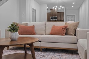A modern living room with a sofa, a coffee table, and a potted plant.