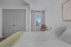 A bedroom with a large bed, a chair, a window with blinds, and a door. - Cozy 3 bedroom Townhome In North Laredo (Laredo)