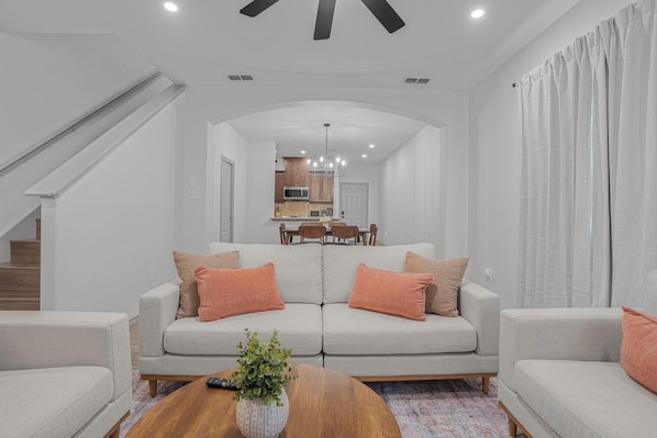 A modern living room with a sofa set, a coffee table with a plant, and a staircase leading to an upper level. - Cozy 3 bedroom Townhome In North Laredo (Laredo)