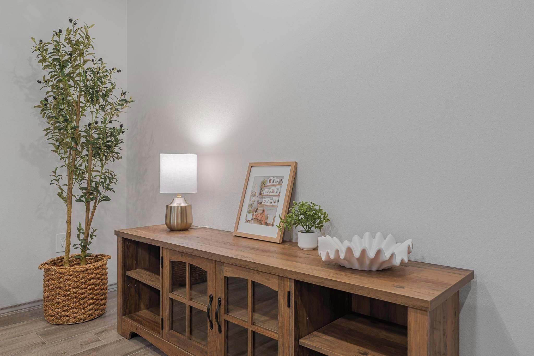 A wooden console table with a lamp, framed picture, and decorative items.