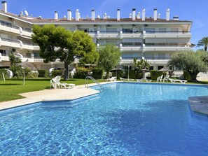 Une piscine à l’eau d’un bleu cristallin, entourée de chaises longues blanches et d’une pelouse bien entretenue.