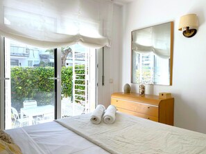 Ein Hotelzimmer mit einem Bett, einem Schminktisch, einem Spiegel und Blick auf Grünfläche.