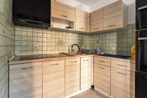 Eine Küche mit Holzschränken, einer schwarzen Dunstabzugshaube, einer gefliesten Rückwand und einem Spülbecken.