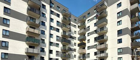 Un edificio residencial de varios pisos con balcones, techo plano y cielo despejado.