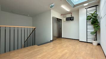 Un interior moderno con piso de madera, una escalera, un ascensor y un tragaluz.