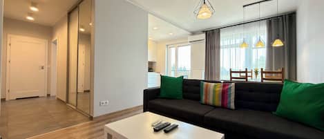 A modern living room with a sofa, a coffee table, and a dining area with a table and chairs.