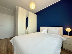 A bedroom with a bed, bedside lamps, and a wardrobe with a mirror.