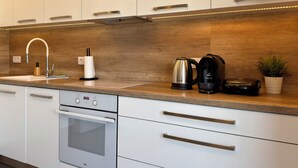 Una cocina moderna con alacenas blancas, electrodomésticos de acero inoxidable y un salpicadero de madera.