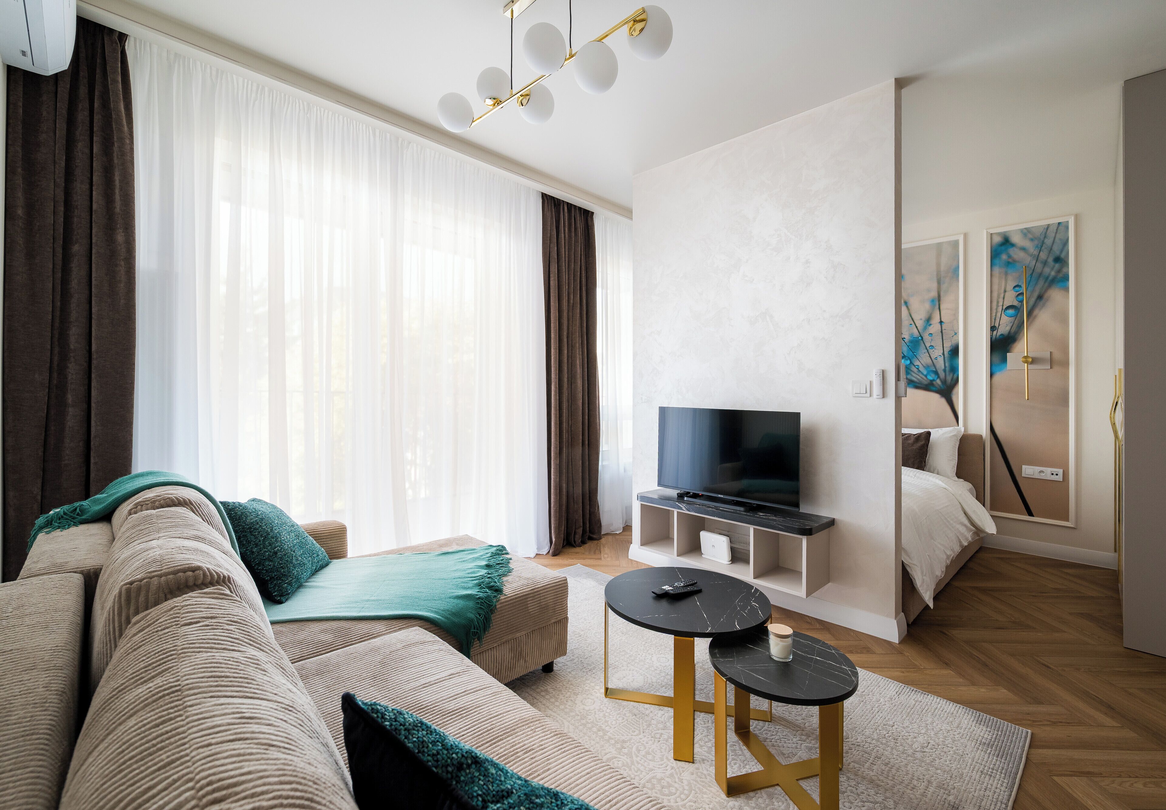 Un salon moderne avec un canapé, une table basse, un téléviseur et des œuvres d’art accrochées au mur.