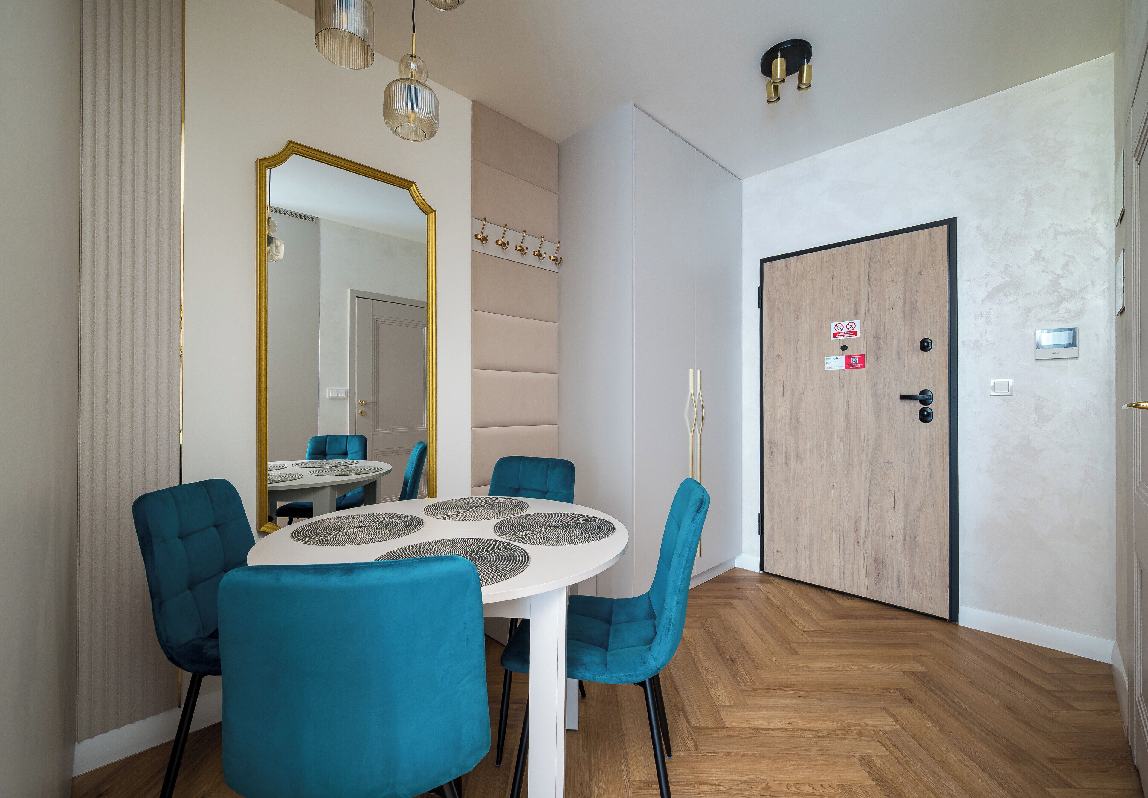 A modern dining area with a round table, blue chairs, and a large mirror.