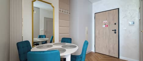A modern dining area with a round table, blue chairs, and a large mirror.