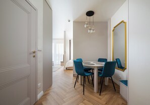 Ein stilvoller Essbereich mit einem runden Tisch, blauen Stühlen und einem Spiegel mit goldener Rahmung.