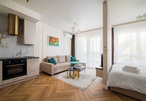 Een moderne, goed verlichte woonruimte met keuken, bank, salontafel en bed.