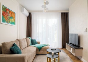 Moderni olohuone, jossa on sohva, sohvapöytä, televisio ja taulu seinällä.