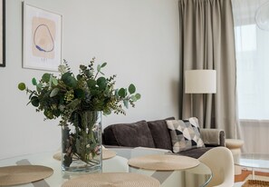 A modern living room with a glass coffee table, a sofa with a patterned throw, and a vase with green foliage. - Krucza City Heart Apartment (Warszawa)