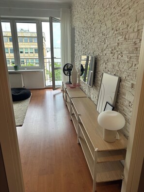 A modern room with a stone wall, a wooden bench, a white sink, and a large window. - Krucza City Heart Apartment (Warszawa)