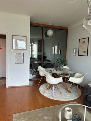 A modern dining area with a glass table, white chairs, and a round rug. - Krucza City Heart Apartment (Warszawa)