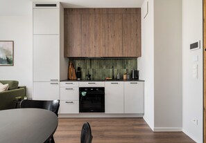 A modern kitchen with white cabinetry, a wooden upper section, and a green backsplash. - Wola Redutowa Superior Apartment (Warszawa)