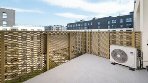 Une terrasse sur le toit avec un sol de couleur beige, une clôture beige et un appareil de climatisation blanc.