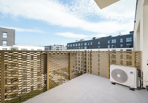 A rooftop terrace with a beige floor, a beige fence, and a white air conditioning unit. - Wola Redutowa Superior Apartment (Warszawa)