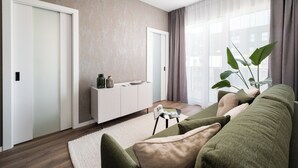 Un salon moderne avec un canapé, une console blanche et une grande fenêtre agrémentée de rideaux.