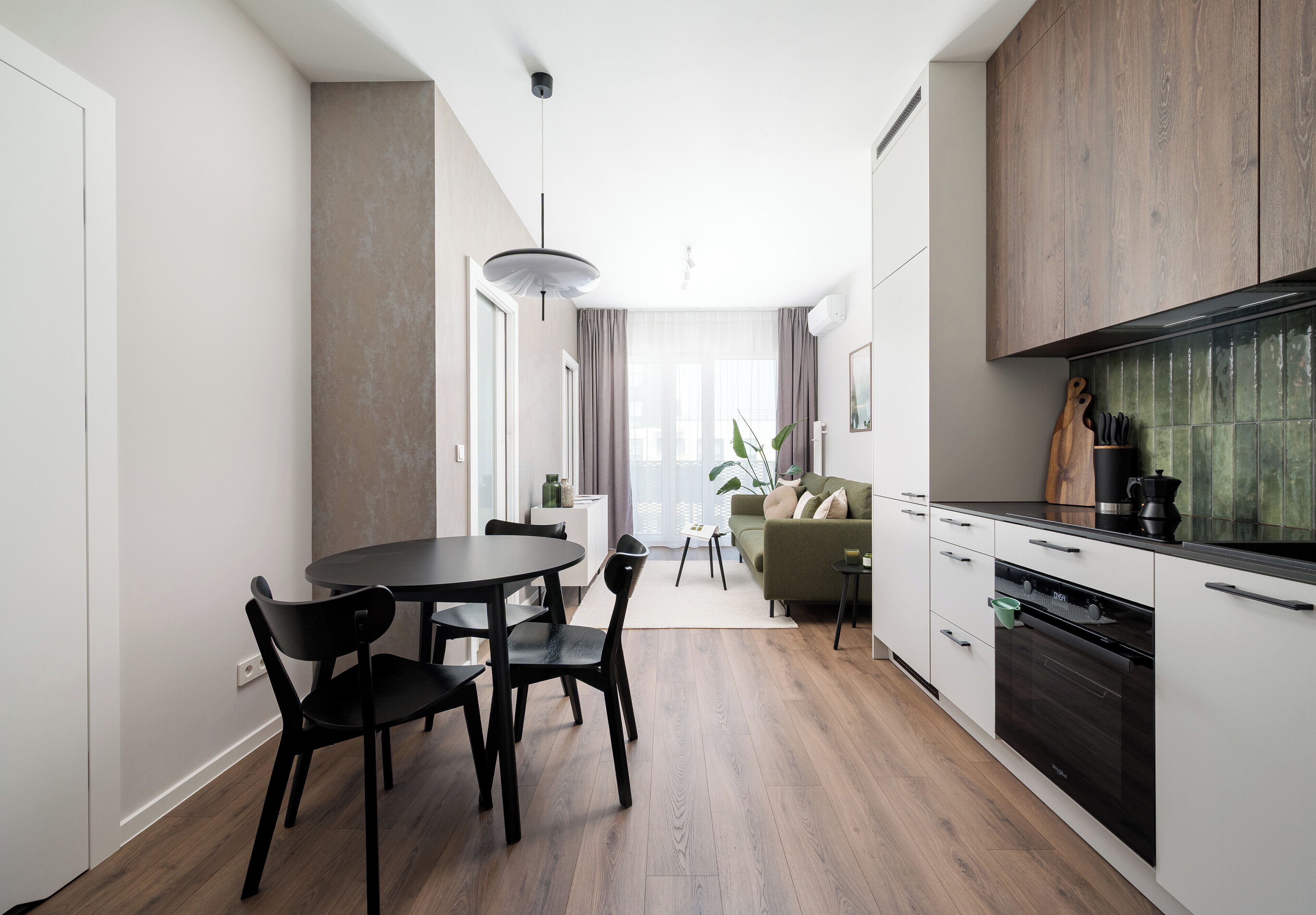 Una cocina moderna con comedor, piso de madera y vista al salón.