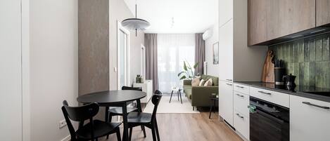 Una cocina moderna con comedor, piso de madera y vista al salón.
