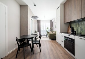 Une cuisine moderne avec un coin repas, un plancher en bois et une vue sur le salon.