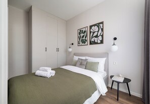 Une chambre à coucher moderne comprenant un lit, une table de chevet, une armoire et deux appliques murales.