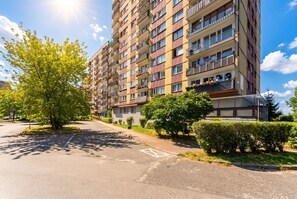A multi-story residential building with balconies, a parking area, and greenery. - Sosnowiec Modern Apartment (Sosnowiec)