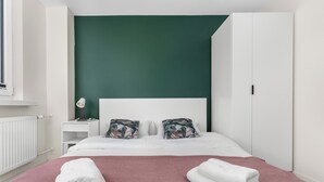 Ein Hotelzimmer mit Bett, Nachttisch, Lampe und Kleiderschrank.