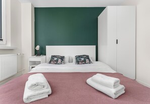 A hotel room with a bed, a nightstand, a lamp, and a wardrobe. - Sosnowiec Modern Apartment (Sosnowiec)