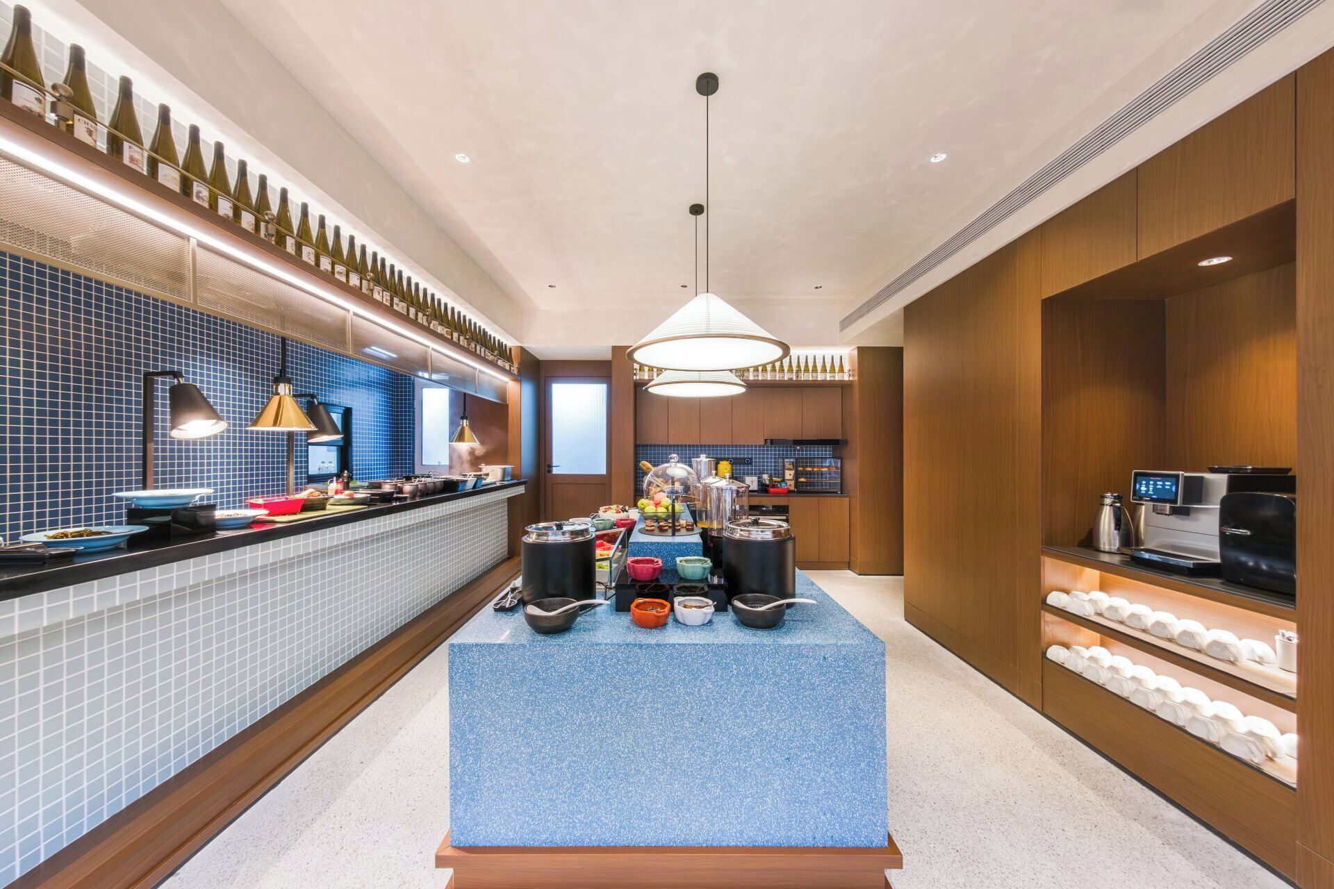Una cocina moderna con una isla central, una alacena para vinos y una zona de café.