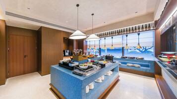 A hotel breakfast area with a buffet setup, including various food items and condiments.